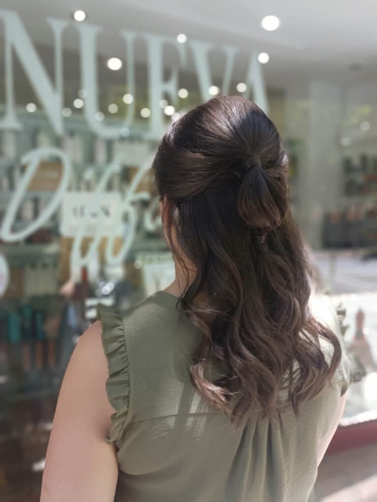 Semirrecogido con volumen en la coronilla y ondas sueltas en una melena castaña, de espaldas con blusa verde