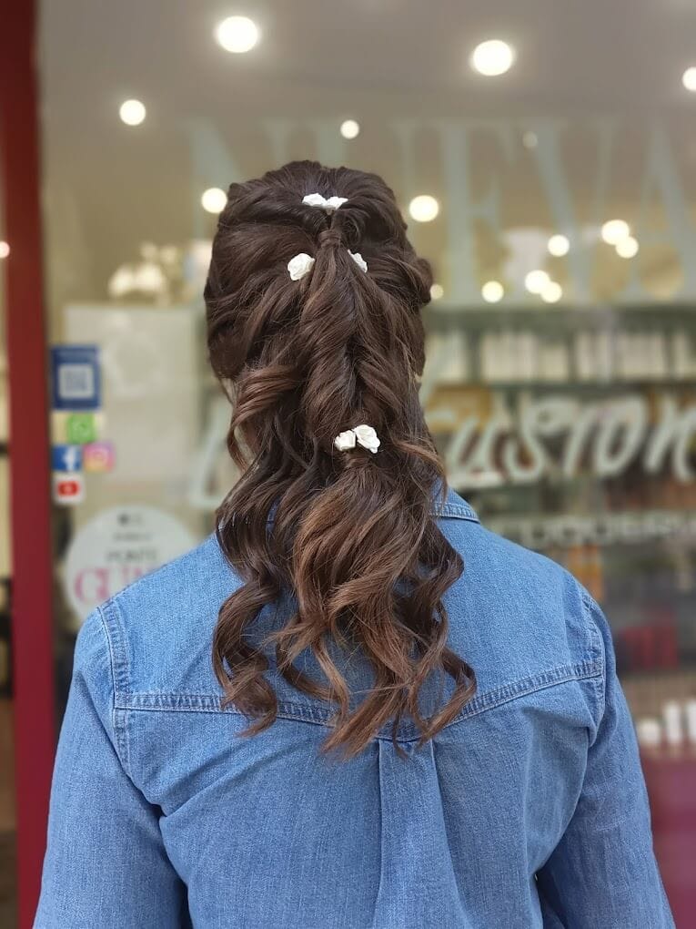 Semirrecogido trenzado con florecillas blancas en una melena castaña ondulada, visto de espaldas con camisa vaquera